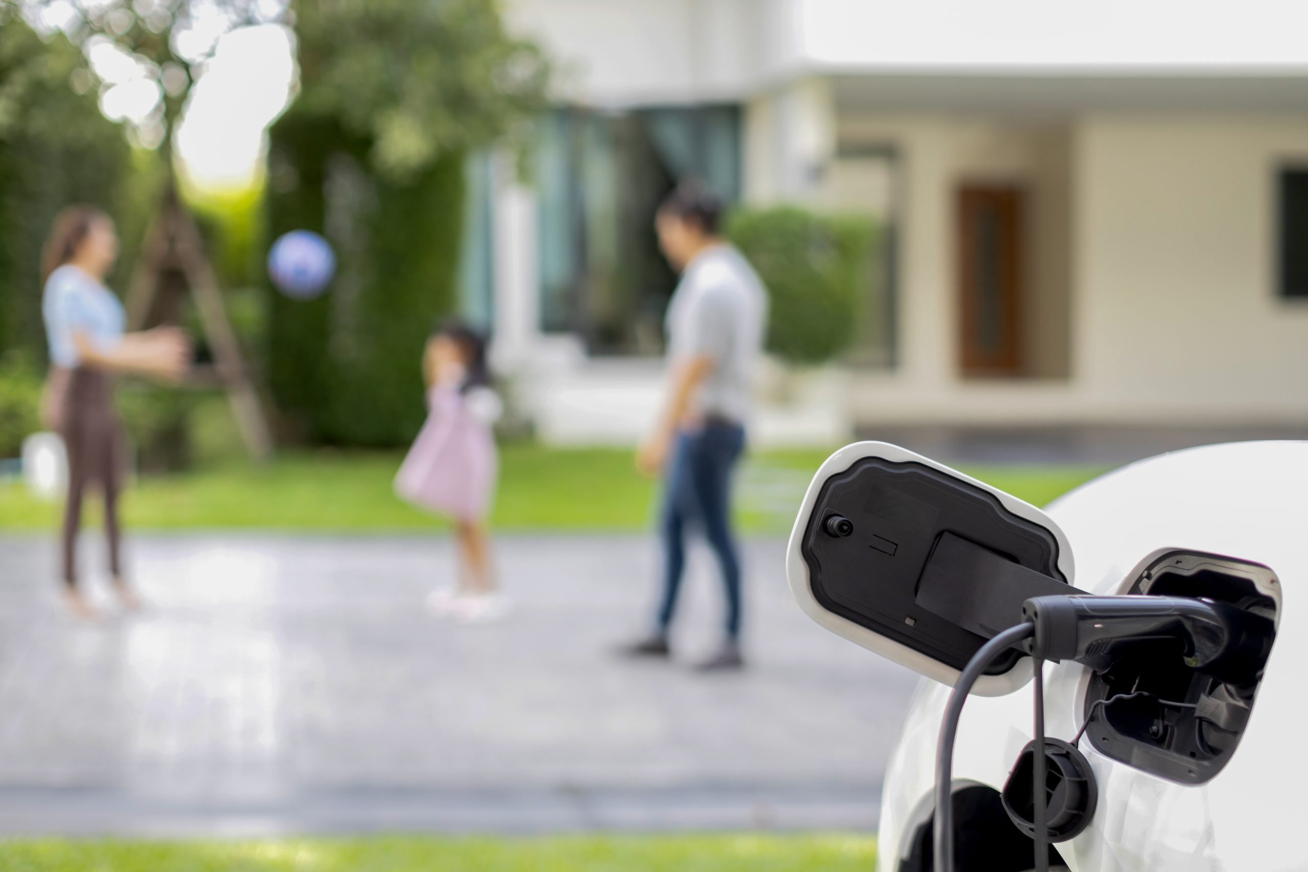 Focus EV charger recharge EV car at home with progressive family in background.